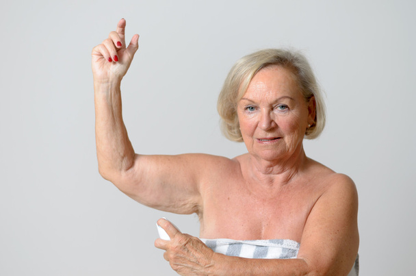 Леді середнього віку застосовує дезодорант на пахві
 - Фото, зображення