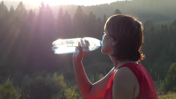 Σιλουέτα της γυναίκας που πόσιμο νερό στα βουνά στο ηλιοβασίλεμα. - Πλάνα, βίντεο