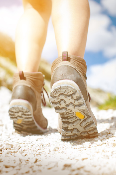 Caminante mujer caminar en un suelo rocoso. Día soleado.Botas de trekking. Mochilero exitoso. Piedra. Paso.
  - Foto, Imagen