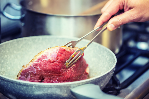 Beef steak. Chef in a restaurant kitchen use ceramic pan for preparation of beef steak - Photo, image