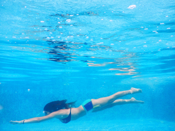 νεαρή γυναίκα Κολυμπήστε υποβρύχια δίπλα στην πισίνα - Φωτογραφία, εικόνα