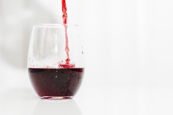 Red wine is pouring into a glass.  - Foto, Imagen