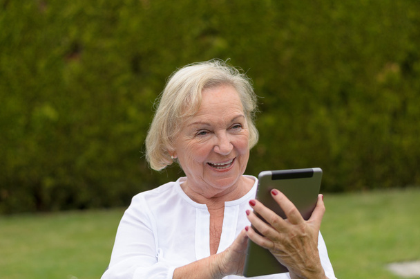 Senior serene woman using a black tablet PC - Фото, изображение