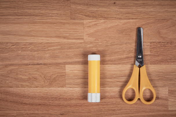 Glue and scissors on a wooden oak table - Фото, зображення