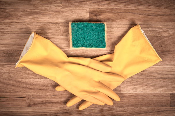 Cleaning gloves and sponge on a brown wooden table - Foto, Bild