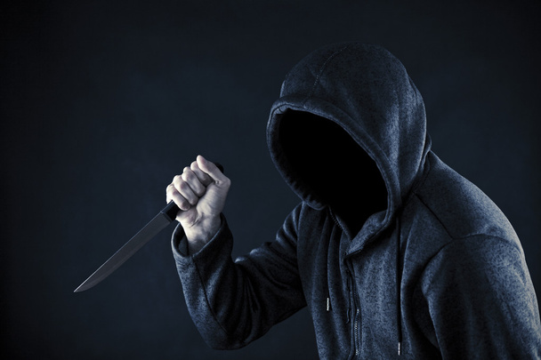 Hombre encapuchado con cuchillo en la oscuridad
  - Foto, imagen