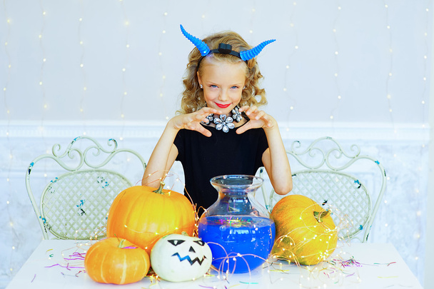 Little girl in demon costume playing with pumpkins - Fotoğraf, Görsel