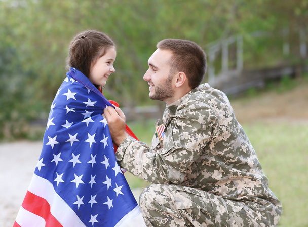 US army soldier with daughter and USA flag in park - Foto, Imagen