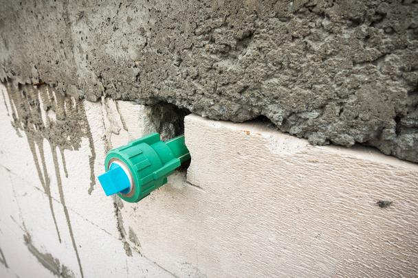 Drinkbaar water pijp ingebed in de muur van het blok. - Foto, afbeelding