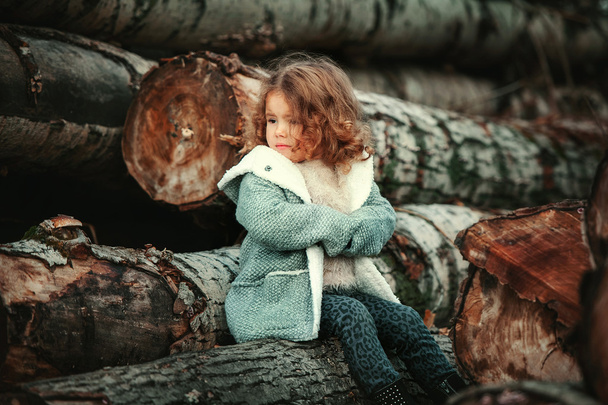 Little upset girl sitting on wood - Foto, immagini