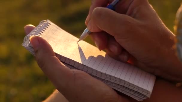 La pluma escribe en el papel desde el bloc de notas. Luz solar
. - Imágenes, Vídeo