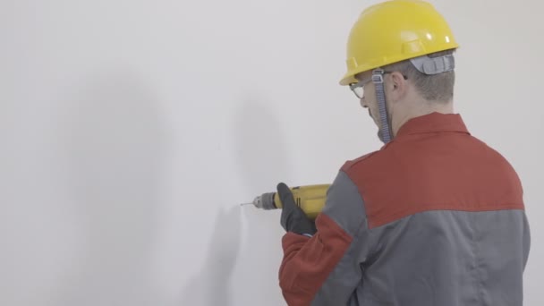Worker using a drilling machine and drilling hole in the wall - Séquence, vidéo