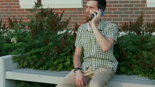 Tezgah ve bir cep telefonu üzerinde konuşurken rahat giyimli adam oturup - Video, Çekim