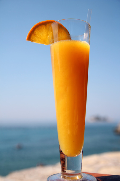 Oranje cocktail tegen blauwe zee en hemel - Foto, afbeelding
