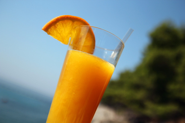 jus d'orange glas tegen zeegezicht - Foto, afbeelding