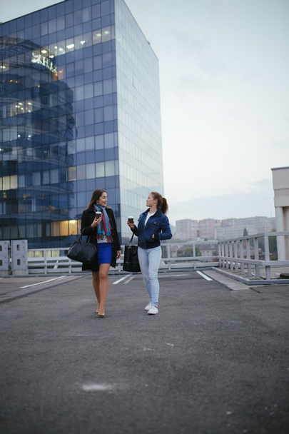 Two modern women friends walking in city and communicating - Foto, Bild