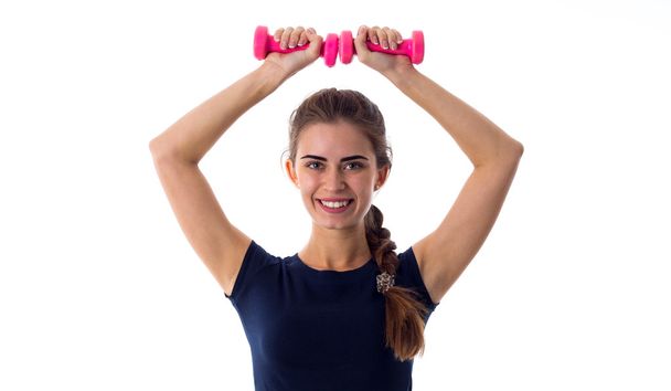 Smiling woman holding two dumbbells over her head - Photo, Image