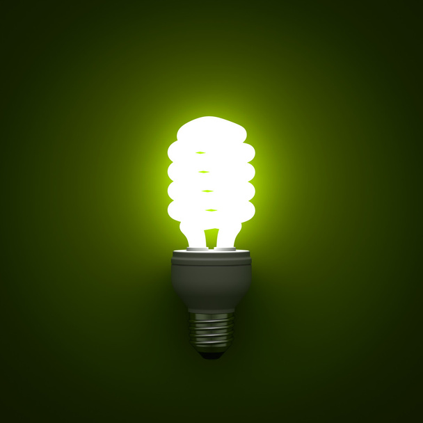 úsporná Kompaktní zářivka žárovka zářící nad zeleným pozadím - Fotografie, Obrázek