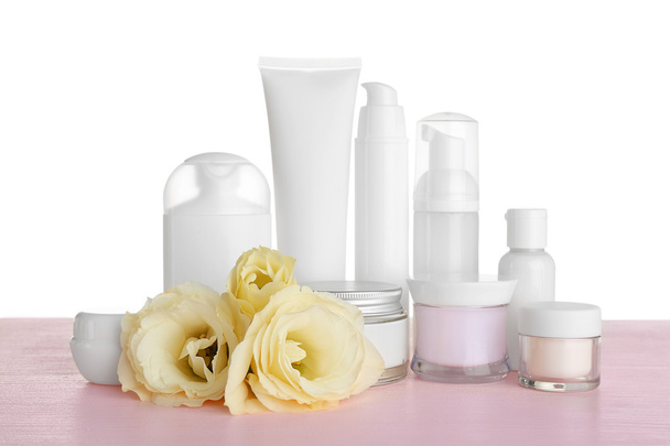 Different cosmetic bottles and eustoma flowers on table - Fotó, kép