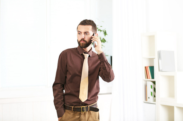 Businessman speaking by mobile phone in office - Fotoğraf, Görsel