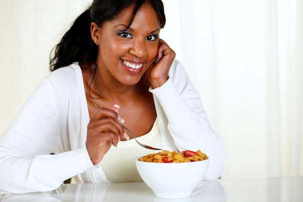 Mulher olhando para você e comendo uma tigela de cereais
 - Foto, Imagem