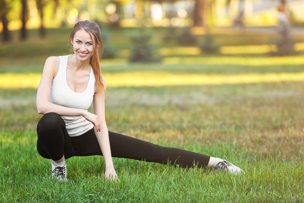 Young woman stretching outdoors - Valokuva, kuva