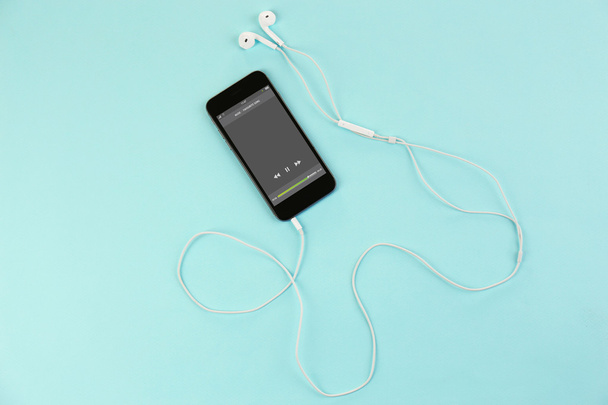 Smartphone with earphones on color background - Valokuva, kuva