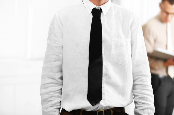 Man adjusting leather tie in office - Zdjęcie, obraz