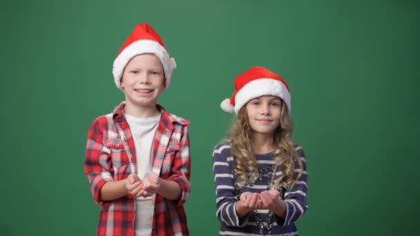 かわいい男の子と女の子に紙吹雪を投げるクリスマス キャップ - 映像、動画