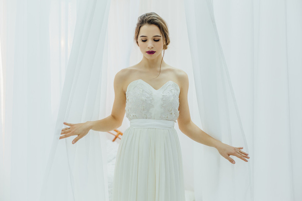 Yong beautiful bride near the white blinds - Foto, immagini