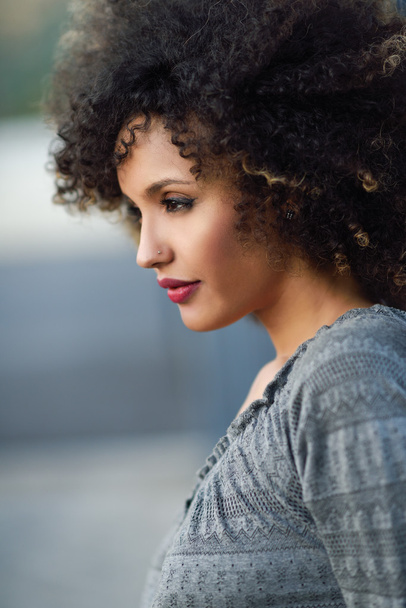 Joven mujer negra con peinado afro sonriendo en el fondo urbano
 - Foto, Imagen