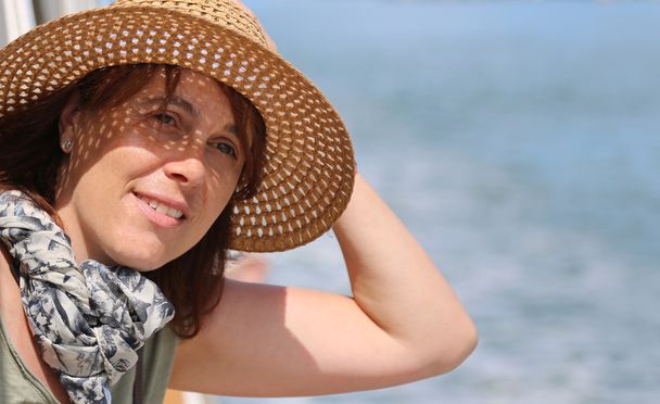 leuke veertig jaar oude vrouw met stro hoed op het cruise schip - Foto, afbeelding