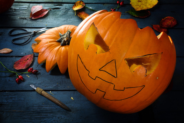 Vyřezávání dýně na halloween, hráli podzimní dekorace na modrý venkovský dřevěný stůl - Fotografie, Obrázek