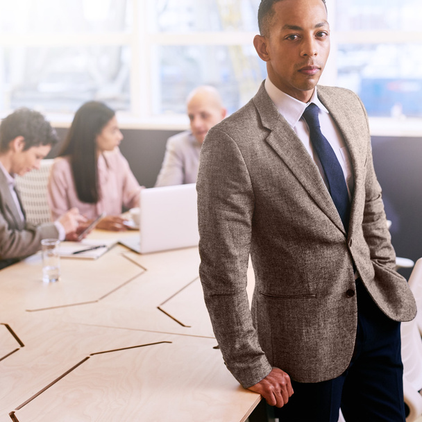 Профессиональный бизнесмен стоит перед коллегами по бизнесу в помещении
 - Фото, изображение