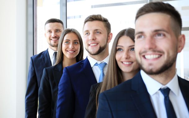 Happy sorrindo equipe de negócios de pé em uma fileira no escritório
 - Foto, Imagem