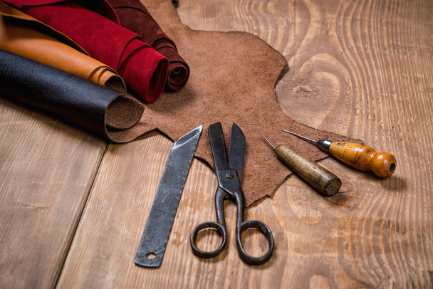 Set of leather craft tools on wooden background. Workplace for shoemaker. - Photo, image