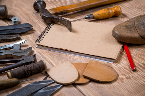 Conjunto de ferramentas, caderno, lápis para sapateiro em um fundo de madeira
. - Foto, Imagem