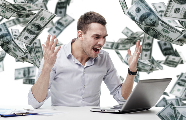 hombre de negocios enojado con el ordenador portátil y dinero cayendo
 - Foto, imagen