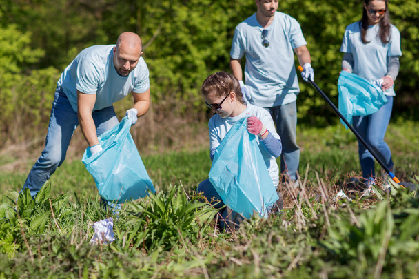 volunteers with garbage bags cleaning park area - 写真・画像