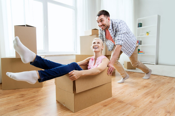 couple with cardboard boxes having fun at new home - Photo, image