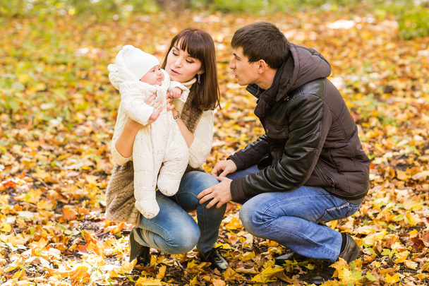 love, parenthood, family, season and people concept - smiling couple with newborn baby in autumn park - Photo, Image