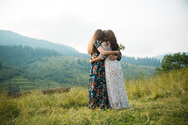 Girls girlfriend dresses rest on the nature in a beautiful mountain meadow - Photo, Image