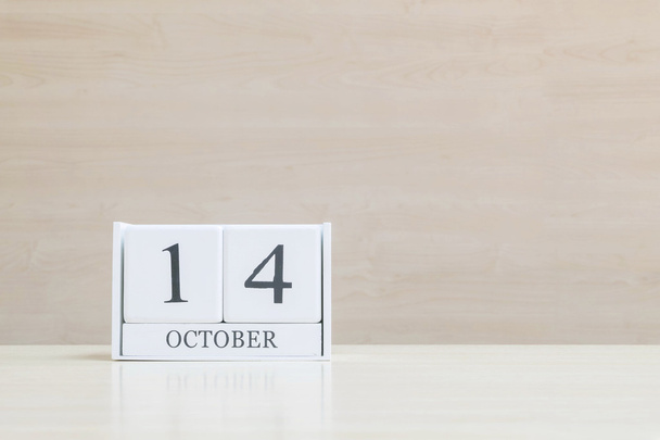 Closeup surface white wooden calendar with black 14 october word on blurred brown wood desk and wood wall textured background with copy space , view another more date in my portfolio - Photo, Image