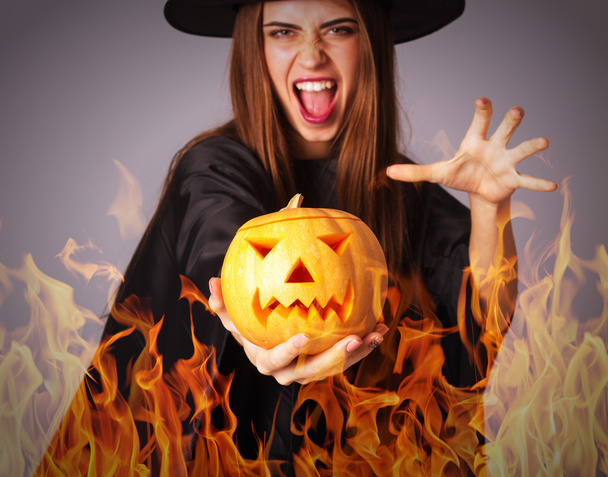 Vrouw in kostuum van heks houden een pompoen in brand - Foto, afbeelding