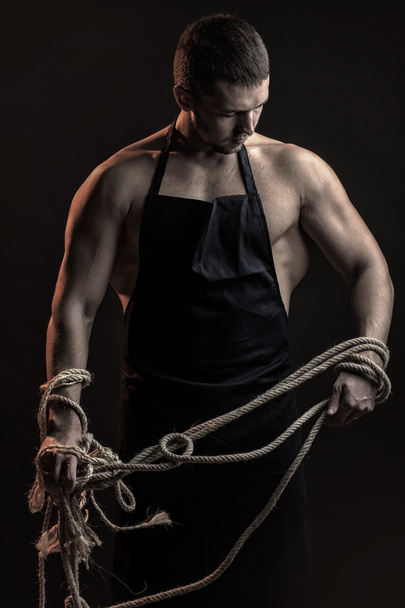 Muscular man in apron with rope - Фото, зображення