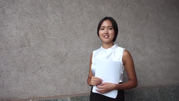 Nuori kaunis liike nainen nainen tyttö muotokuva pidä asiakirjoja taustalla toimistorakennus ulkona
 - Materiaali, video