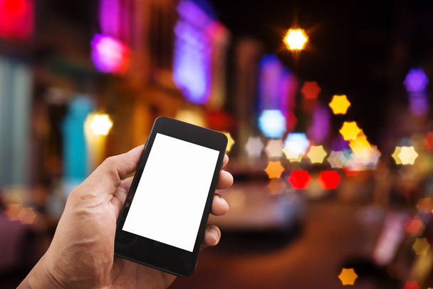 Ruka s chytrý telefon mobilní na noční město - Fotografie, Obrázek