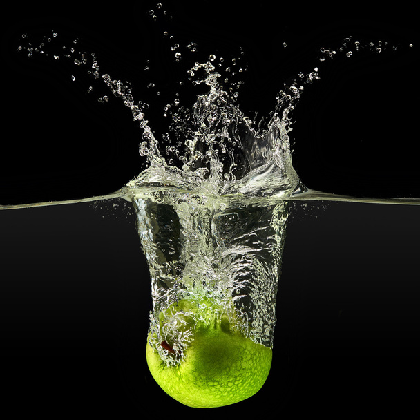Green apple falling in water on black background - Photo, image