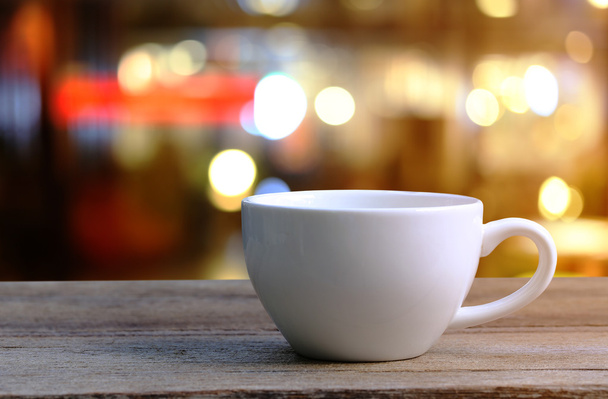 Witte koffie cup op houten tafel in coffeeshop achtergrond wazig. - Foto, afbeelding