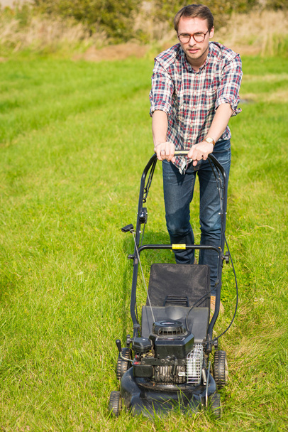 Young man mowing the grass  - Фото, изображение